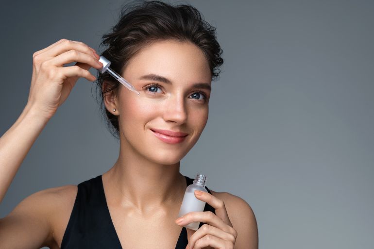 Woman applying hyaluronic serum on her face with pipette. Photo of attractive woman with perfect makeup on gray background. Beauty concept; Shutterstock ID 1779995840; purchase_order: ajnet; job: ; client: ; other: