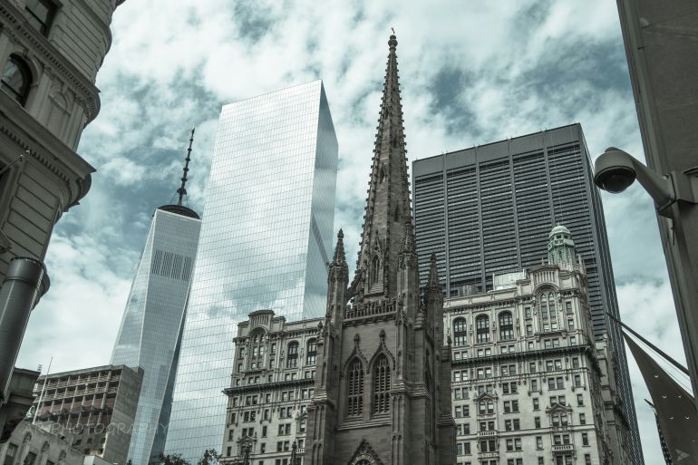 Low Angle View Of St Patrick Cathedral And One World Trade Center Against Cloudy Sky - stock photo