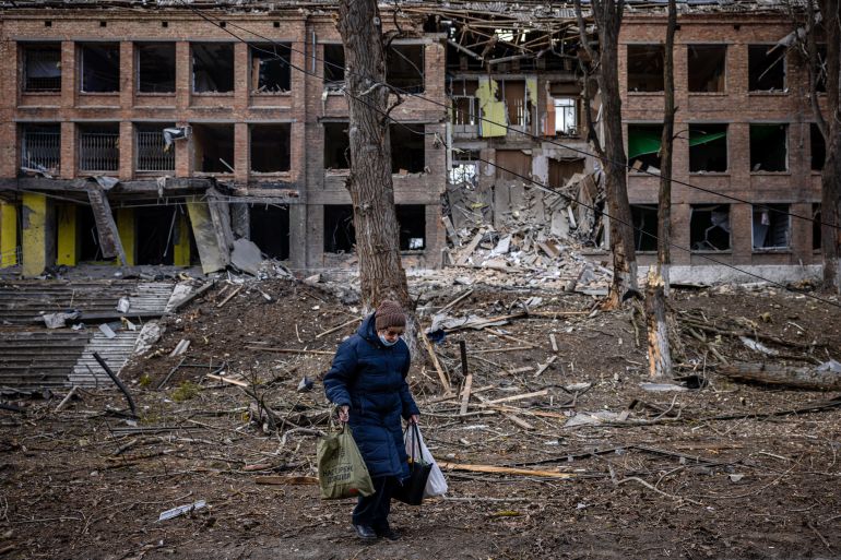 A woman walks in front of a destroyed building after a Russian missile attack in the town of Vasylkiv, near Kyiv, on February 27, 2022. - Ukraine's foreign minister said on February 27, that Kyiv would not buckle at talks with Russia over its invasion, accusing President Vladimir Putin of seeking to increase "pressure" by ordering his nuclear forces on high alert. (Photo by Dimitar DILKOFF / AFP)