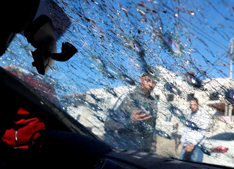 People look at a cracked windscreen with bullet holes at the scene where three Palestinian gunmen were killed by Israeli forces, in Nablus in the Israeli-occupied West Bank February 8, 2022. REUTERS/Mohamad Torokman TPX IMAGES OF THE DAY