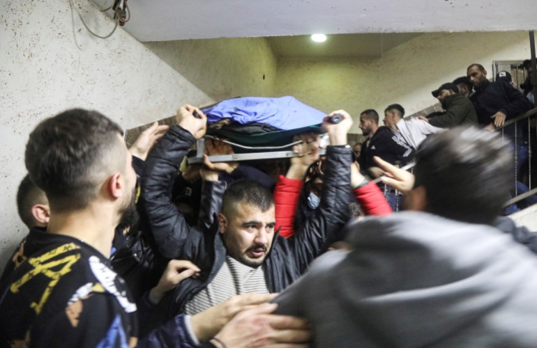 People carry a body of a Palestinian gunman, who was killed along with two other militants by Israeli forces, at a hospital in Nablus, in the Israeli-occupied West Bank, February 8, 2022. REUTERS/Raneen Sawafta