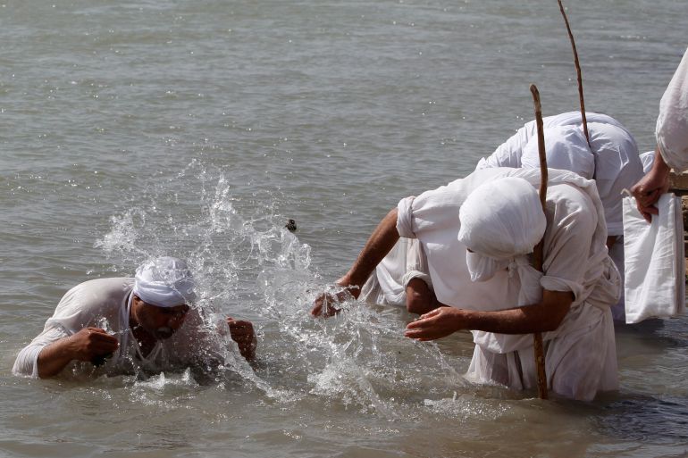 A Mandaean priest baptises a worshipper in the Tigris river during the Benja festival in Baghdad