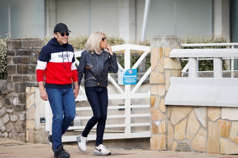 French President Emmanuel Macron, candidate for his re-election in the 2022 French presidential election, walks with his wife Brigitte Macron, on the eve of the second round of the presidential election, in Le Touquet-Paris-Plage, France, April 23, 2022. REUTERS/Johanna Geron