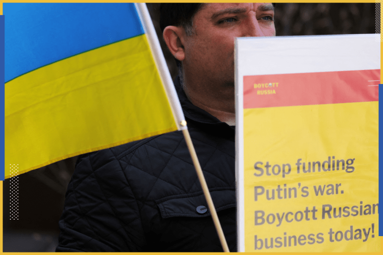 A Ukraine supporter holds a sign and a Ukrainian flag on Park Avenue outside the offices of Philip Morris International Inc to protest their continued business in Russia during a demonstration in Manhattan, New York City