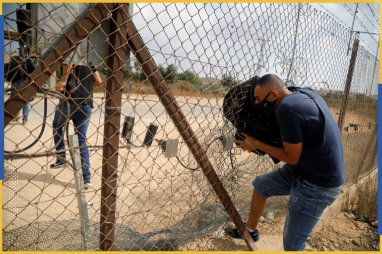 A Palestinian man ducks through an opening in a fence between the Israeli-occupied West Bank and Israel, as he heads to Israel August 12, 2020. Picture taken August 12, 2020. REUTERS/Raneen Sawafta