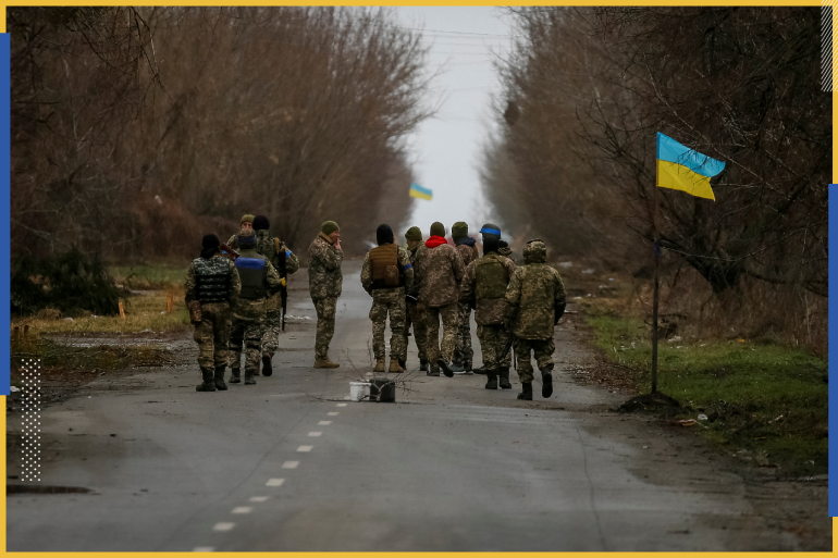 Ukrainian service members walk near a Ukrainian flag, amid Russia's invasion of Ukraine, in the village of Kozarovychi, in Kyiv region, Ukraine April 2, 2022. REUTERS/Gleb Garanich