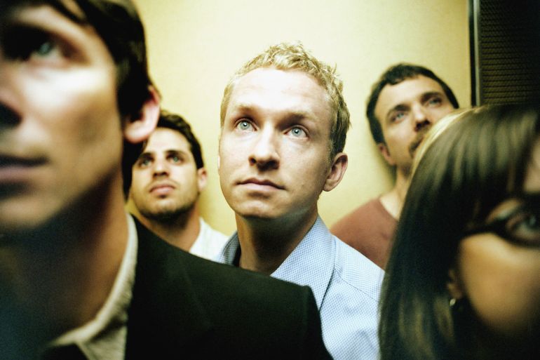 People in elevator, close up (focus on blond man)