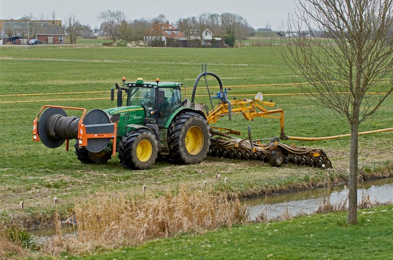 YSBRECHTUM, THE NETHERLANDS - MARCH 1, 2019: A John Deere tractor with a Tjalma slurry injection installation (in Dutch: sleepslang zode bemester) injecting liquid manure in a meadow. Low-emission.
