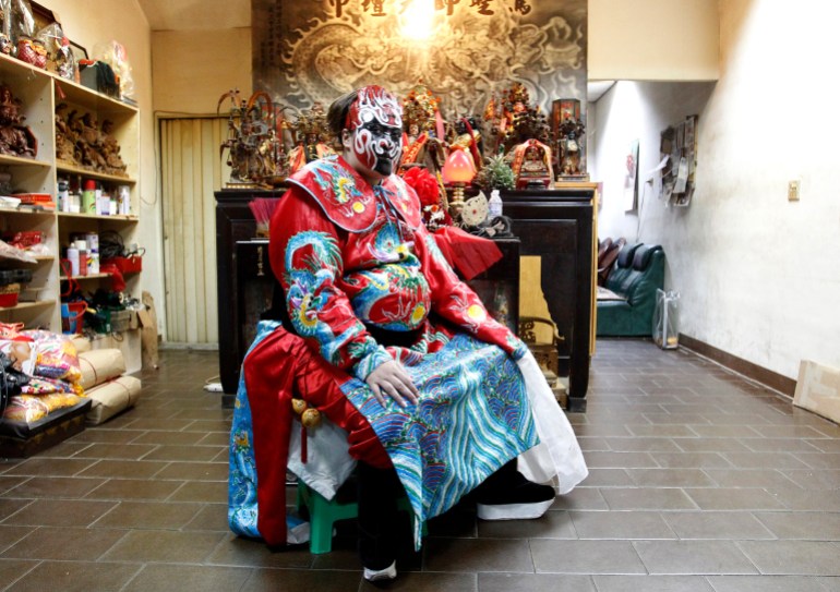 A woman who is dressed up as Zhongkui, the traditional Chinese masculine deity who captures evil spirits in temple festivals, poses for a photograph in Taitung county