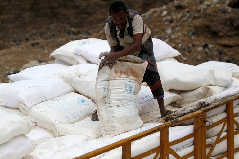 A worker disposes of sacks of World Food Program wheat flour which is reportedly expired or spoiled, on the outskirts of Sanaa
