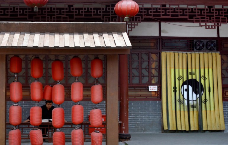 A priest reads as he waits at a desk behind red lanterns at the Qingyanggong Taoist Temple in the south-western Chinese city of Chengdu