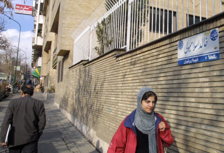 WOMAN WALKS PAST A SIGN FOR KHALED ISLAMBOULI STREET IN TEHRAN.