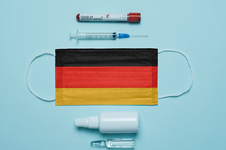 Blood tube for test detection of virus Covid-19 Omicron Variant with positive result, medicine mask with Germany flag superimposed and vaccine. New Variant of the Covid-19 Omicron