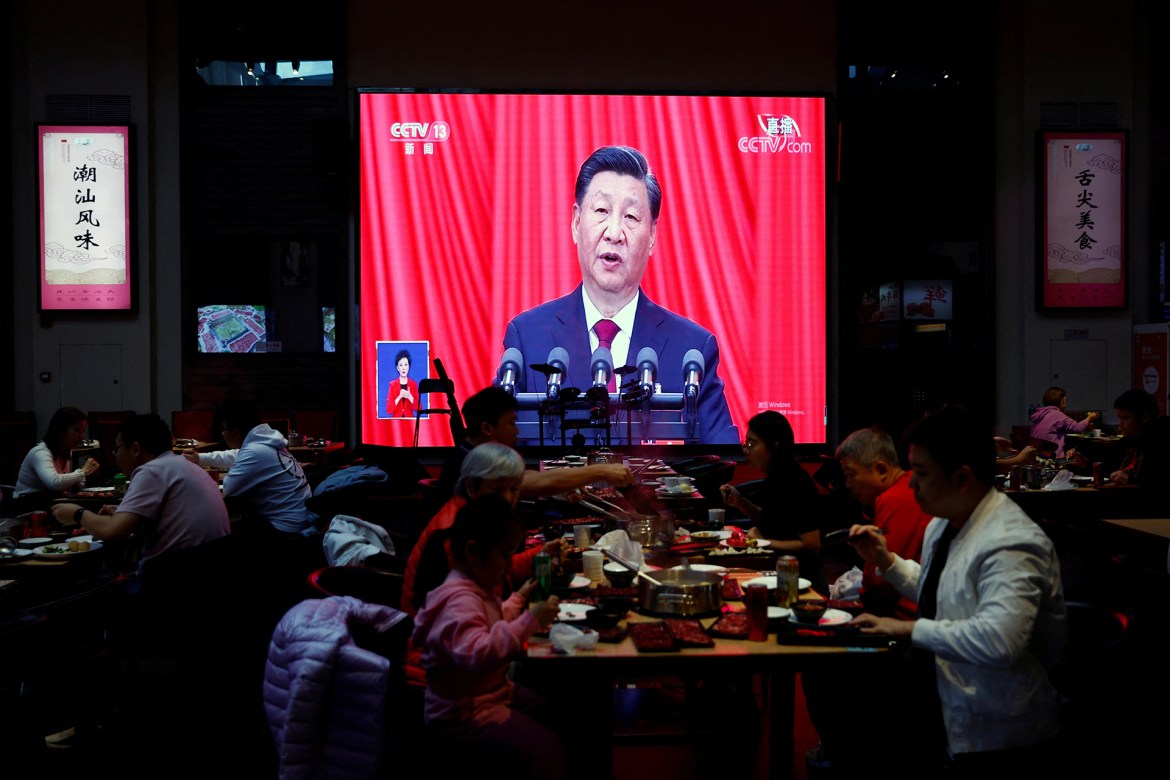 Diners at a restaurant in Beijing eat in front of a screen showing a live broadcast of Xi's speech at the opening ceremony of the Congress. [Tingshu Wang/Reuters]