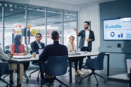 Diverse Modern Office: Businessman Leads Business Meeting with Managers, Talks, uses Presentation TV with Statistics, Infographics. Digital Entrepreneurs Work on e-Commerce Project.