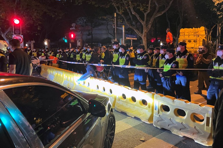 Police officers stand behind barricades and cordon at the site where a protest against COVID-19 curbs took place the night before, following the deadly Urumqi fire, in Shanghai, China November 27, 2022. REUTERS/Josh Horwitz