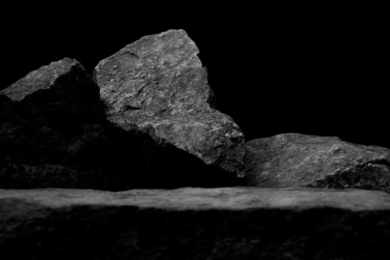 A Blurred Foreground Rock Shelf for a Product Display, Showing Selective Focus to the Background Stones with Natural Worn Texture with Close Detail to the Ancient Small Boulders.