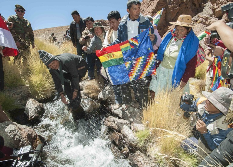 Bolivia's President Evo Morales (2nd L) touches the waters of Silala springs, south of La Paz