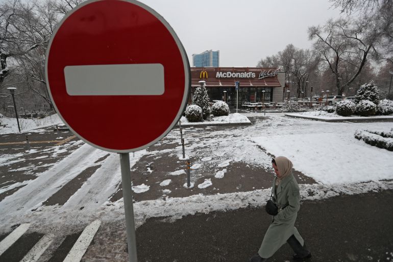 A woman walks past a closed McDonald's restaurant in Almaty