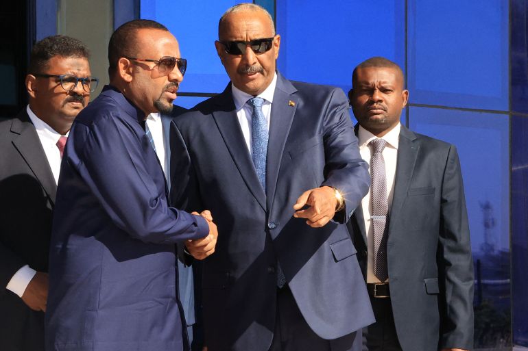Ethiopian Prime Minister Abiy Ahmed (L) walks alongside Sudanese Army Chief Abdel Fattah al-Burhan (C) at Khartoum Airport during a welcome ceremony on January 26, 2023. (Photo by AFP) / The erroneous mention[s] appearing in the metadata of this photo by has been modified in AFP systems in the following manner: [byline is STR] instead of [ASHRAF SHAZLY]. Please immediately remove the erroneous mention from all your online services and delete it from your servers. If you have been authorized by AFP to distribute it to third parties, please ensure that the same actions are carried out by them. Failure to promptly comply with these instructions will entail liability on your part for any continued or post notification usage. Therefore we thank you very much for all your attention and prompt action. We are sorry for the inconvenience this notification may cause and remain at your disposal for any further information you may require.
