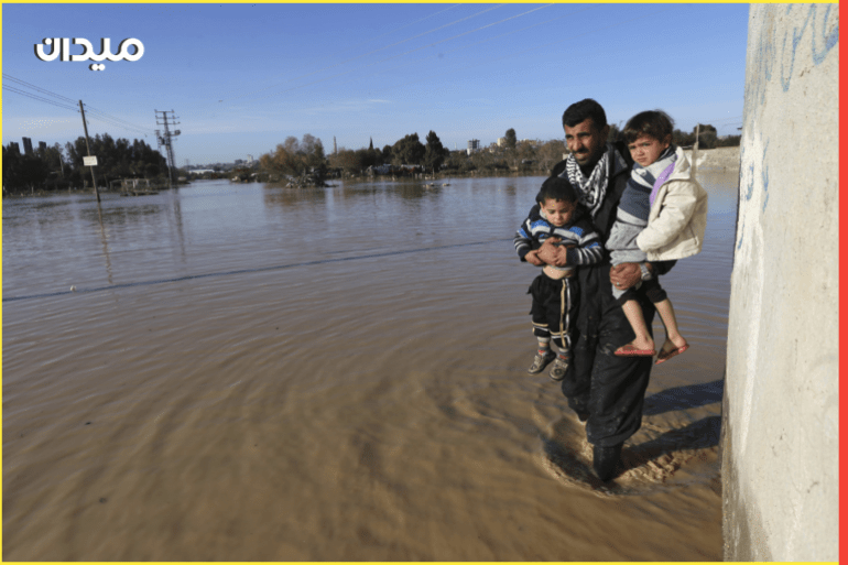 A Palestinian man carries children as he evacuates them in the village of Al-Moghraga after it was flooded by rain water, near central Gaza Strip February 22, 2015. REUTERS/Ibraheem Abu Mustafa (GAZA - Tags: ENVIRONMENT)