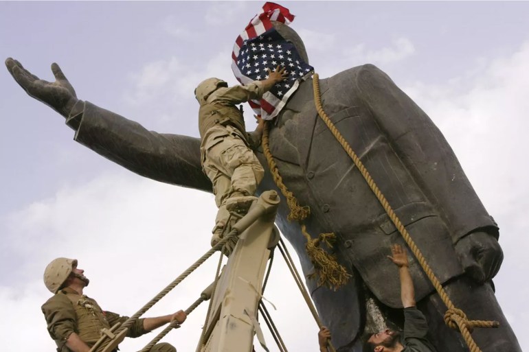 Cpl. Edward Chin covers the face of a statue of Saddam Hussein with an American flag before toppling the statue in downtown in Bagdhad in 2003. Moments later the flag was removed.JEROME DELAY / AP file
