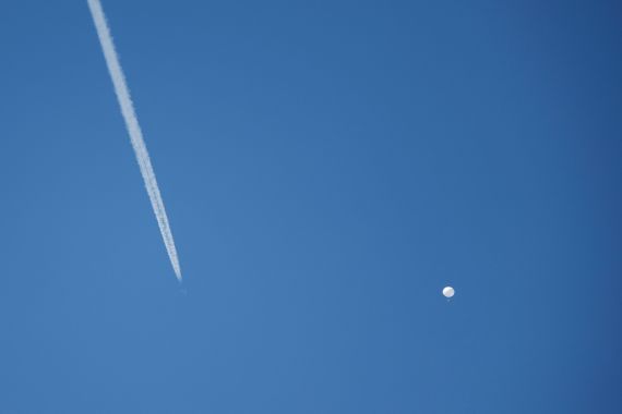 A jet flies by a suspected Chinese spy balloon as it floats off the coast in Surfside Beach