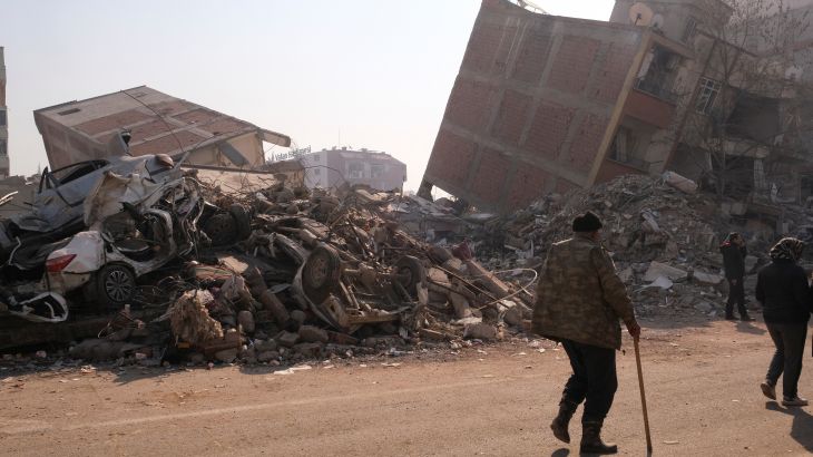 People walk by demolished buildings following the deadly earthquake in Maras