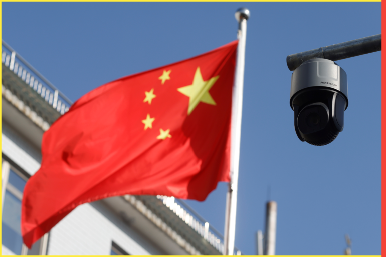 A security surveillance camera overlooking a street is pictured next to a nearby fluttering flag of China in Beijing, China November 25, 2021. Picture taken November 25, 2021. REUTERS/Carlos Garcia Rawlins