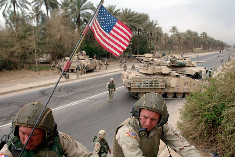 U.S. Army Spc. Micki Nixon, right, and Ssg. Ronnie Lafferty sit atop their Bradley fighting vehicle while infantrymen seach for weapons in Baghdad, Iraq Tuesday, April 15, 2003. Nixon is from Jacksonville, FL. and Lafferty from Burlington, N.C. and both are with the A Company 3rd Battalion 7th Infantry Regiment. (AP Photo/John Moore)
