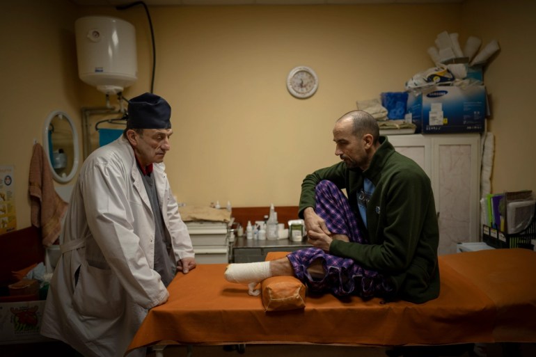 Ukrainian doctor Yurii Kuznetsov speaks to landmine victim Oleksandr Kolisnyk at the hospital in Izyum. [Vadim Ghirda/AP Photo]