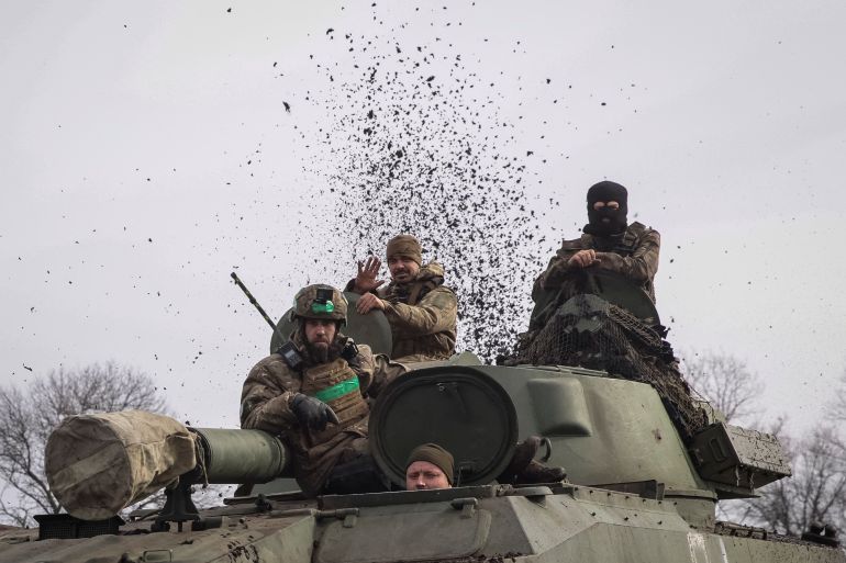 Ukrainian service members ride a self-propelled howitzer near Bakhmut