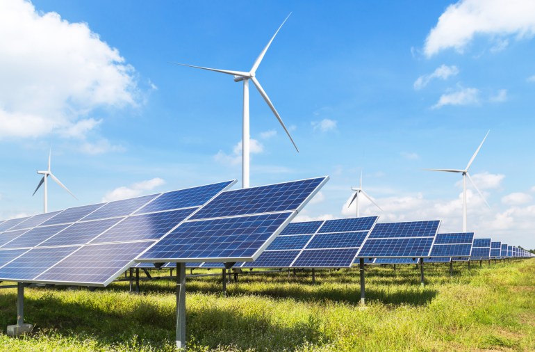 Solar panels and wind turbines generating electricity is solar energy and wind energy in hybrid power plant systems station use renewable energy to generate electricity with blue sky; Shutterstock ID 1520902583; purchase_order:al jazeera; job:; client:; other: