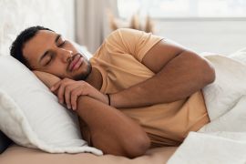 Sleeping Arabic Male Lying In Bed Holding Hands Near Face Resting Head On Pillow In Bedroom At Home. Asleep Man Napping Relaxing In The Morning. Healthy Rest And Recreation Concept shutterstock_2151888233