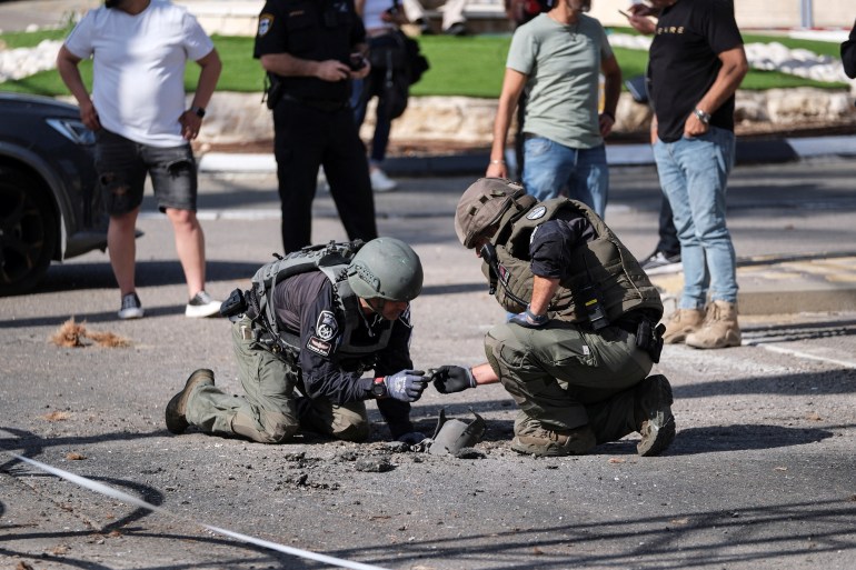 Israeli security personnel check remains of a rocket in Shlomi