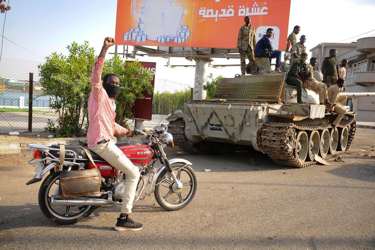 A man raises his arm in support as he drives near Sudanese army soldiers loyal to army chief Abdel Fattah al-Burhan, manning a position in the Red Sea city of Port Sudan, on April 20, 2023. More than 300 people have been killed since the fighting erupted April 15 between forces loyal to al-Burhan and his deputy, Mohamed Hamdan Daglo, who commands the paramilitary Rapid Support Forces (RSF). (Photo by AFP)