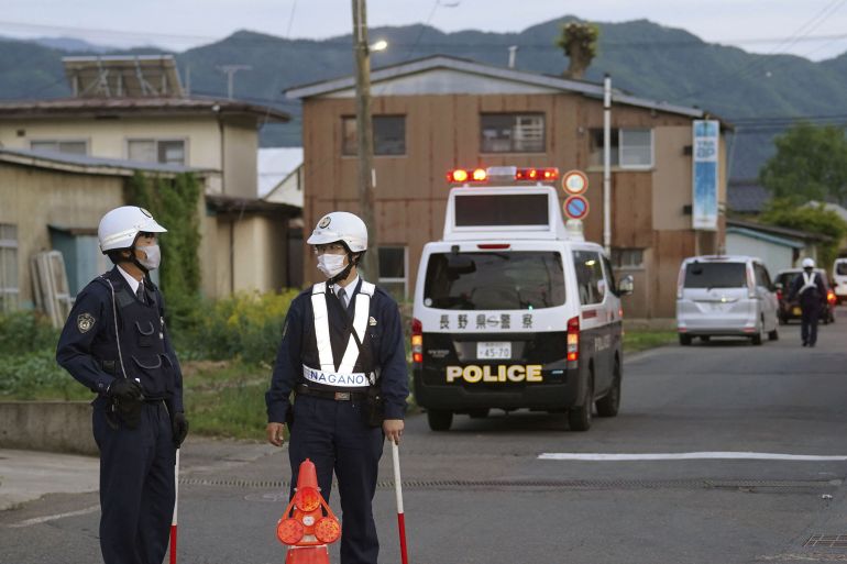 Police officers stand near the scene of a stabbing and shooting incident in Nakano