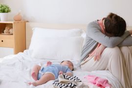 authentic shot of asian mother has postpartum depression with her baby who is lying on bed