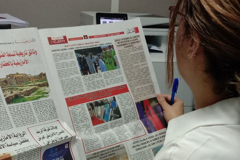 الصورة 2: / سيدة تفتح الصفحة الأمازيغية في أحد أعداد جريدة العلم/ مصدر الصورة: الجزيرة