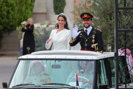 الأمير الحسين بن عبد الله وزوجته الأميرة رجوة يلوحان في أثناء مغادرتهما قصر زهران في عمان بعد عقد قرانهما (الفرنسية)
