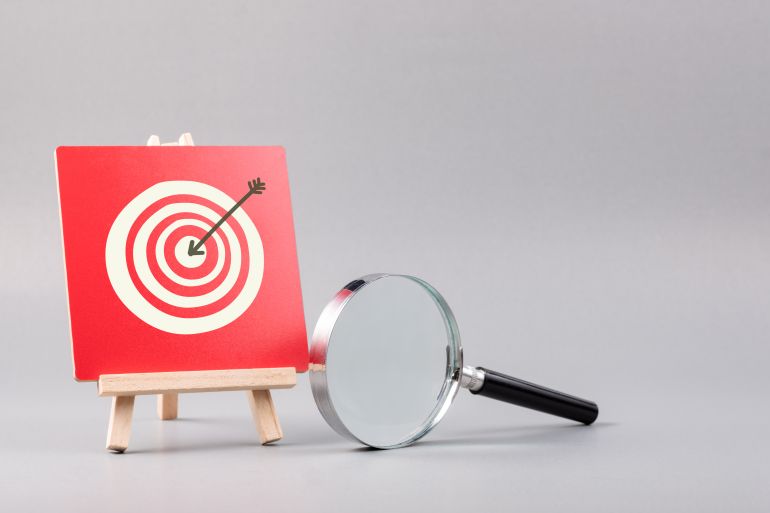 Magnifying glass and target accuracy on wood sign, business plan and marketing strategy, target customer concept shutterstock_1916639504