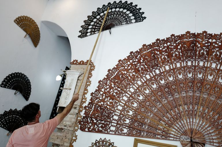 Cuban artisan Jose Miguel R. Cadalso organizes large wooden hand fans at his house in Trinidad, Sancti Spiritus province, Cuba, on June 20, 2023. - Cadalso has specialized in the production of huge wooden hand fans inspired by local religious art and visual references to utilitarian objects from the slavery era in the town of Trinidad, founded in 1514. (Photo by ADALBERTO ROQUE / AFP)