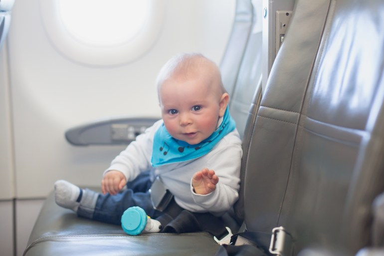 Cute little baby boy, playing with toys on board of aircraft, traveling
