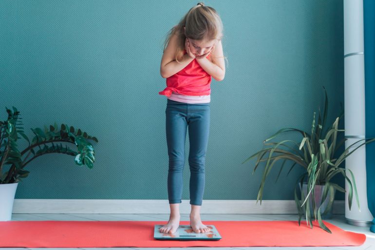 Kid after sports yoga exercises, find out weight on a scale. Loss in percentage of fat. Children fears of dieting