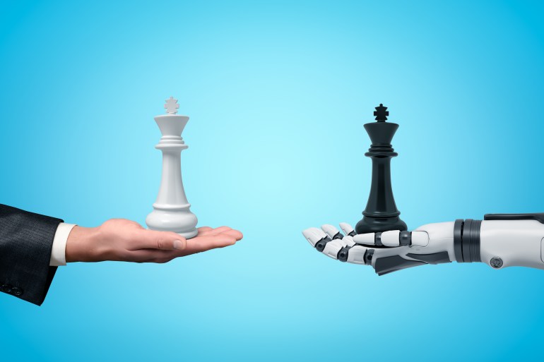Side view of human hand holding white chess king and android robot hand holding black chess king opposite one another on light blue background. Diplomacy. Artificial intelligence. Man vs Machine.