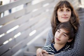 Mother and son sitting on wooden stairs outdoors - stock photo