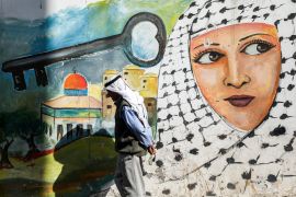 A man walks past a graffiti mural depicting a Palestinian woman clad in a keffiyeh scarf next to a depiction of a key above the Dome of the Rock, in the Jenin camp for Palestinian refugees in the north of the occupied West Bank on September 10, 2020. - In Palestinian refugee camps in the Israeli-occupied West Bank some residents are taking up arms for a potential power struggle when president Mahmud Abbas, 85, finally leaves the stage. Abbas, leader of the dominant Fatah movement and of the Palestinian Authority (PA), has promised elections in 2021, for the first time in almost 15 years. In Jenin refugee camp, in the north of the occupied West Bank, the walls are plastered with posters showing young Palestinian men wearing keffiyeh scarfs around their necks and clutching AK-47 assault rifles. (Photo by JAAFAR ASHTIYEH / AFP)