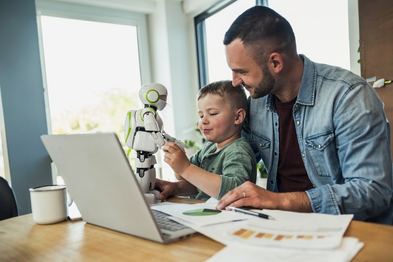 Smiling man looking at son playing with robot at home - stock photo