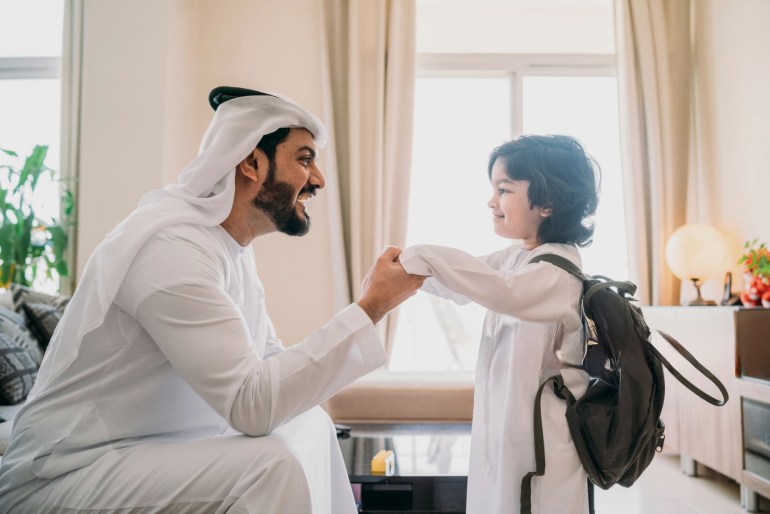 Back to school time: arab dad saying hello to his son - stock photo Back to school time: arab dad saying hello to his son