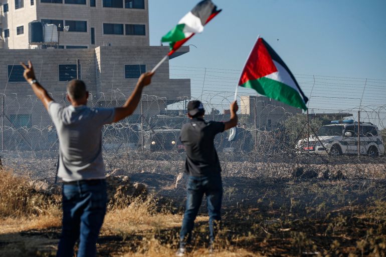 Palestinian wave the national flags during clashes with Israeli forces following a demonstration against an Israeli court issued demolition notice of buildings in the Palestinian village of Beit Sahur in the occupied West Bank of Bethlehem, on July 20, 2019. Palestinians accuse Israel of using security as a pretext to force them out of the area, meant to be under Palestinian Authority civilian control under the Oslo accords, as part of long-term efforts to expand settlements and roads linked them. An Israeli high court ruling in June 2019 dismissed a petition by Palestinian residents requesting the cancellation of a military order prohibiting construction, and residents received a 30-day notice from Israeli authorities informing them of their intent to demolish the homes. (Photo by HAZEM BADER / AFP)